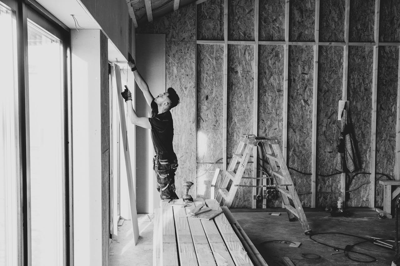 classes-01 Black and white photo of a worker installing drywall indoors, Falun, Sweden.